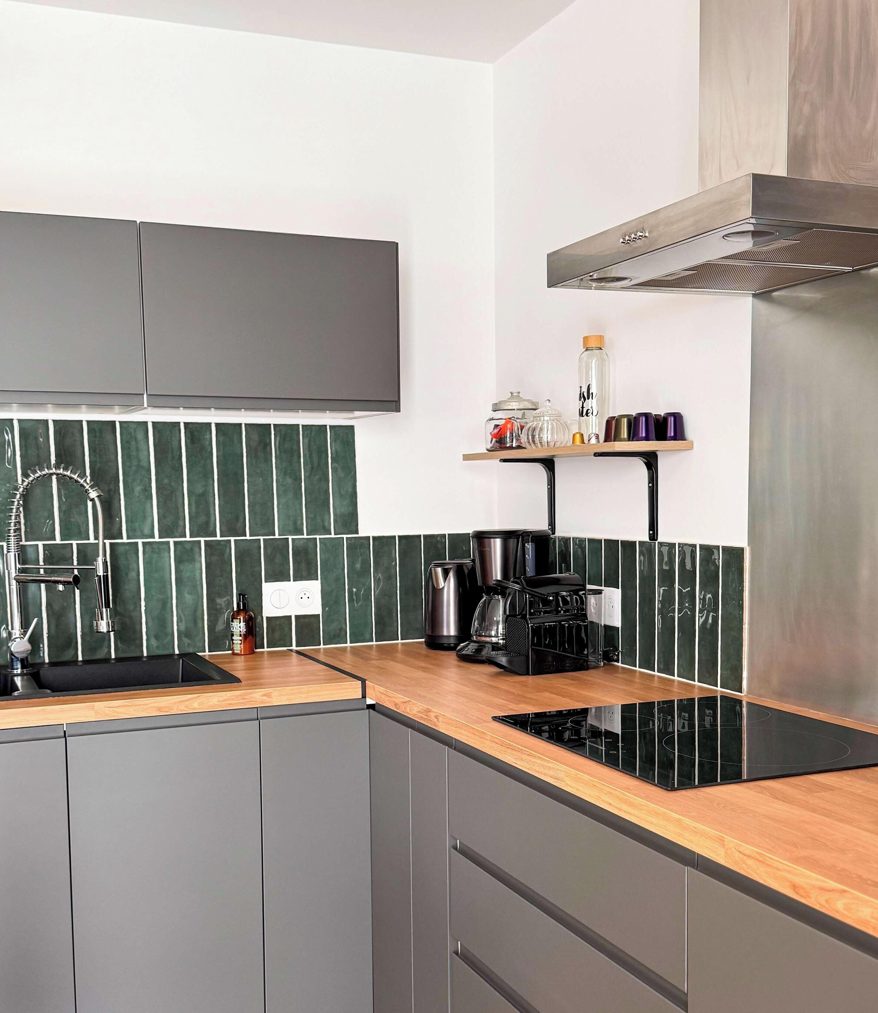 A modern kitchen with a black stove, a coffee maker, and a shelf with kitchen items.
