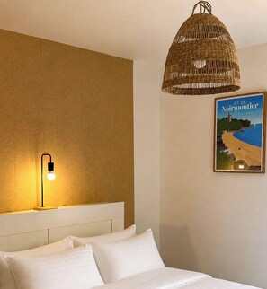 A hotel room with a bed, a wall-mounted light, a wicker ceiling light, and a poster of Île de Noirmoutier. - Tranquiloue - Maison Neuve - 18 min du Puy du Fou (Les Herbiers)