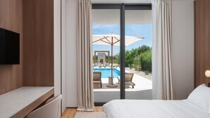 Ein Hotelzimmer mit Bett, Fernseher, Schreibtisch und Blick auf den Poolbereich.