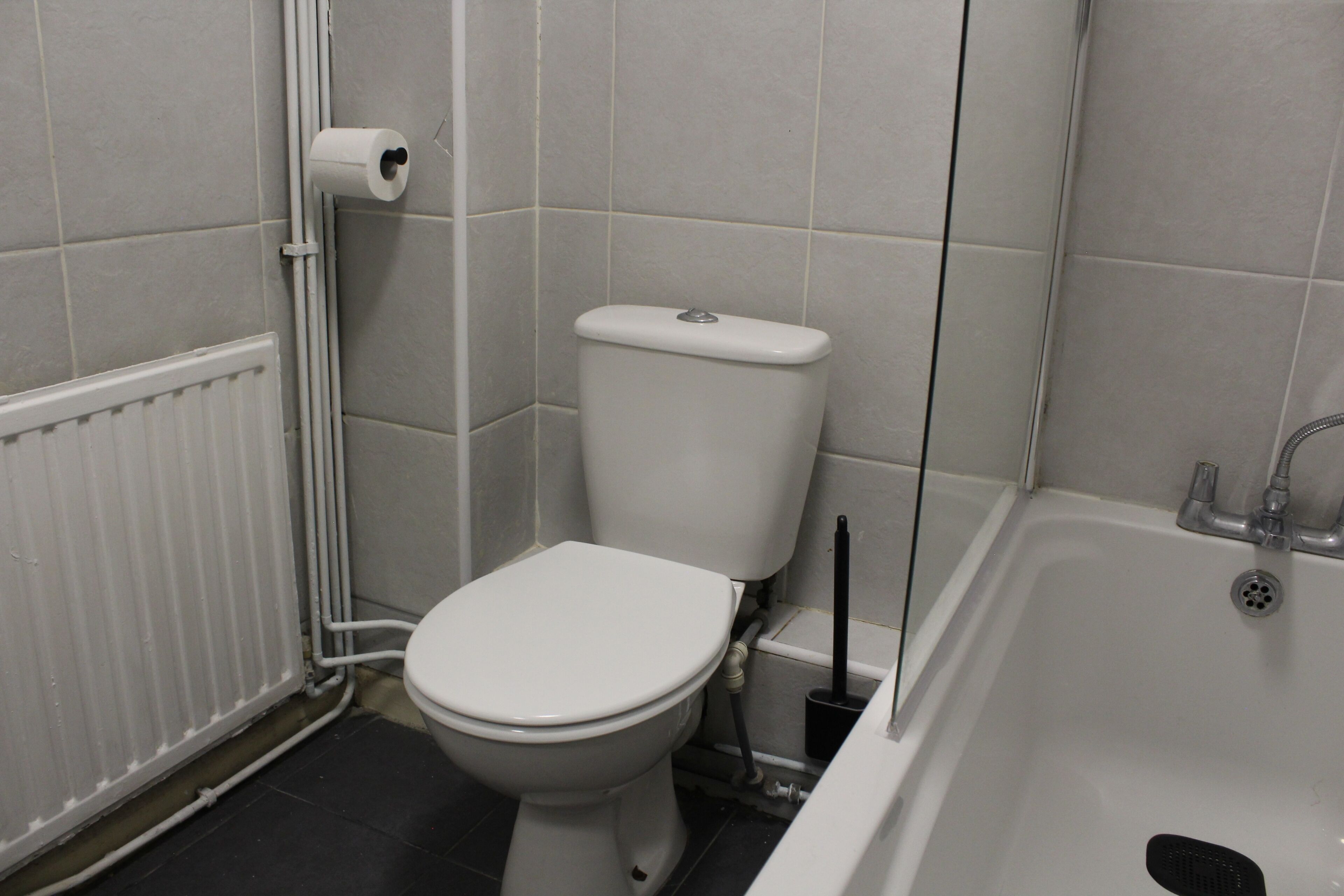 Ein Badezimmer mit Toilette, Badewanne und Heizkörper.