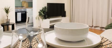 A dining area with a table set for two, including plates, bowls, glasses, and cutlery.