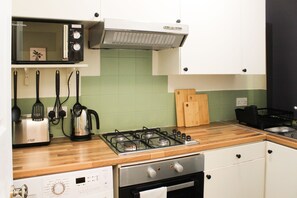 Een keuken met een magnetron, broodrooster, waterkoker, fornuis en vaatwasser.
