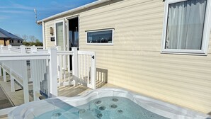 Una casa móvil con jacuzzi, una cerca blanca y una ventana con cortinas.