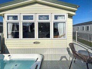 Ein überdachter Außenbereich mit Whirlpool, einer Terrasse und einem Gebäude mit mehreren Fenstern.