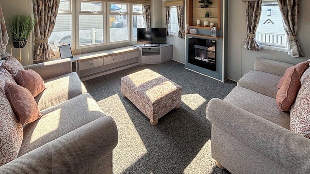 A living room with a sofa set, a television, a fireplace, and a window with curtains. - Sunnymede B8 - UKC9571 (Ingoldmells)