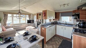 A compact living space with a dining area, kitchenette, and a television in the living room. - Sunnymede B8 - UKC9571 (Ingoldmells)