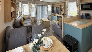 Ett kompakt bostadsutrymme med en soffa, ett matbord och ett litet kök.