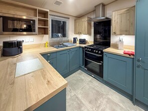 Eine moderne Küche mit Mikrowelle, Herd, Spüle und Holzschränken.
