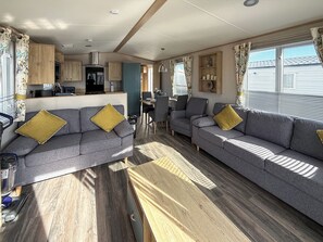 Ein kompaktes Wohnmobil-Interieur mit zwei Sofas, einer Essecke und einer Küchenzeile.