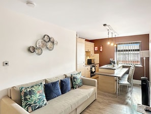 A living room with a sofa, a dining area with a table and chairs, a kitchen with appliances, and decorative wall art. - BK302 Billow - UKC9592 (Blackpool)