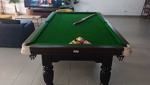Ein Billardtisch mit Kugeln in einem Raum mit Fernseher und einer Couch.