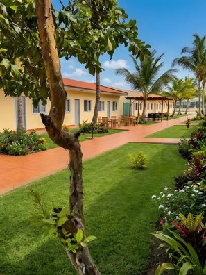 A hotel with a paved walkway, outdoor seating, and a well-maintained lawn. - Casa Erica (Soyo)