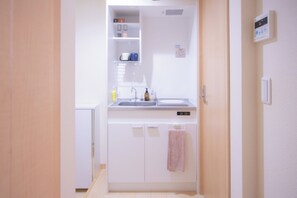 A compact kitchen with a sink, cabinets, and a towel hanging on the door.
