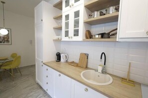 Eine moderne Küche mit weißen Schränken, einer Holz Arbeitsplatte, einem Spülbecken und einem Essbereich mit gelben Stühlen.