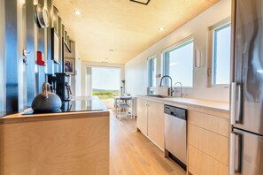 A modern kitchen with wooden cabinets, stainless steel appliances, and a view of the outdoors.