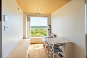 Una habitación con un ventanal grande, una mesa y una silla.