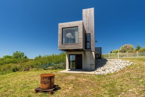 Una casa moderna con un diseño arquitectónico único, destacando una fachada de madera y un gran ventanal.