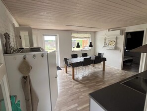 A modern kitchen with a dining area, wooden flooring, and a view of the outdoors. - 5 Star Holiday Home in Vaeggerlose (Vaeggerlose)