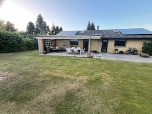 A house with a patio, outdoor seating, and solar panels on the roof. - 5 Star Holiday Home in Vaeggerlose (Vaeggerlose)