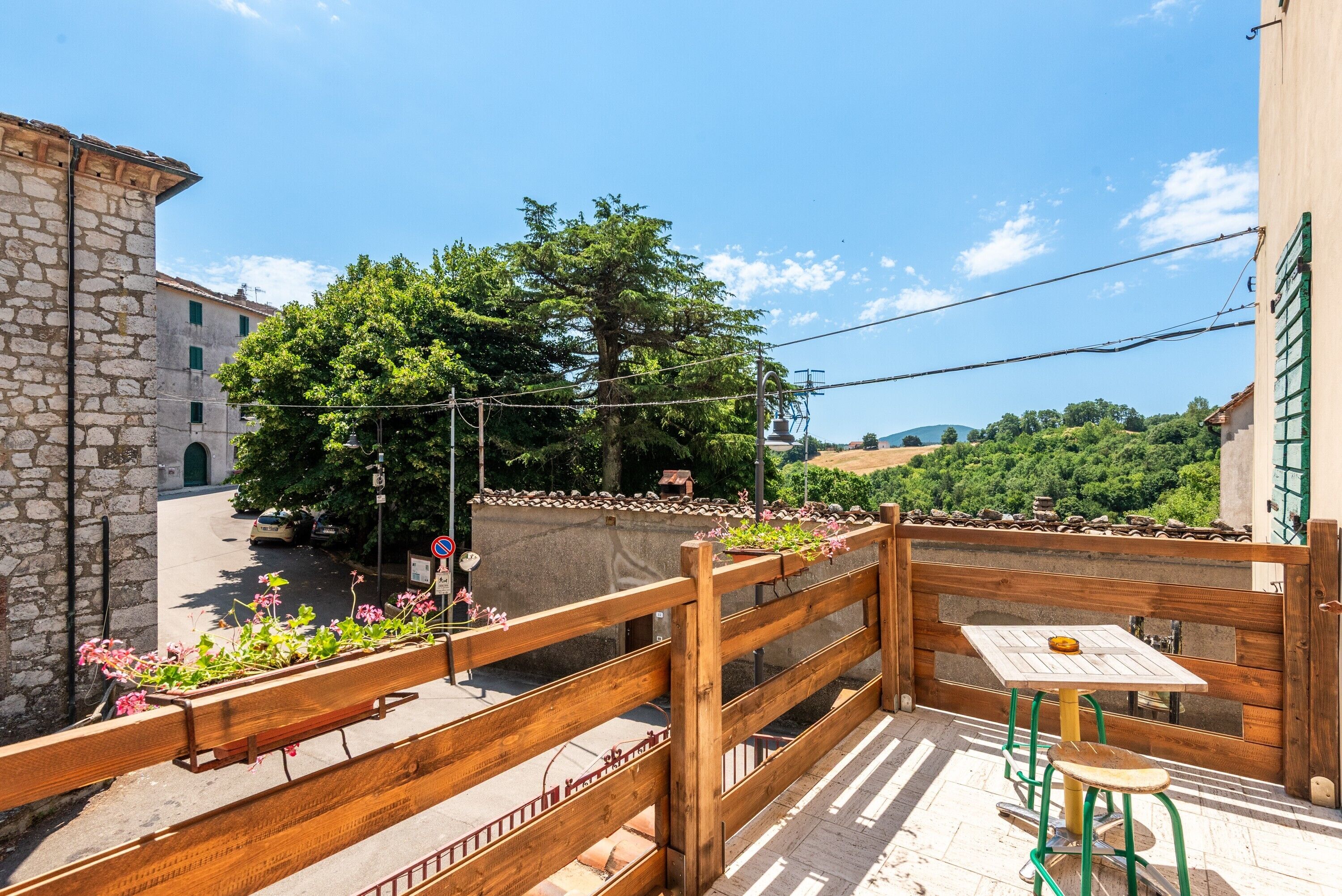 A balcony with a wooden railing, a table, and a chair.