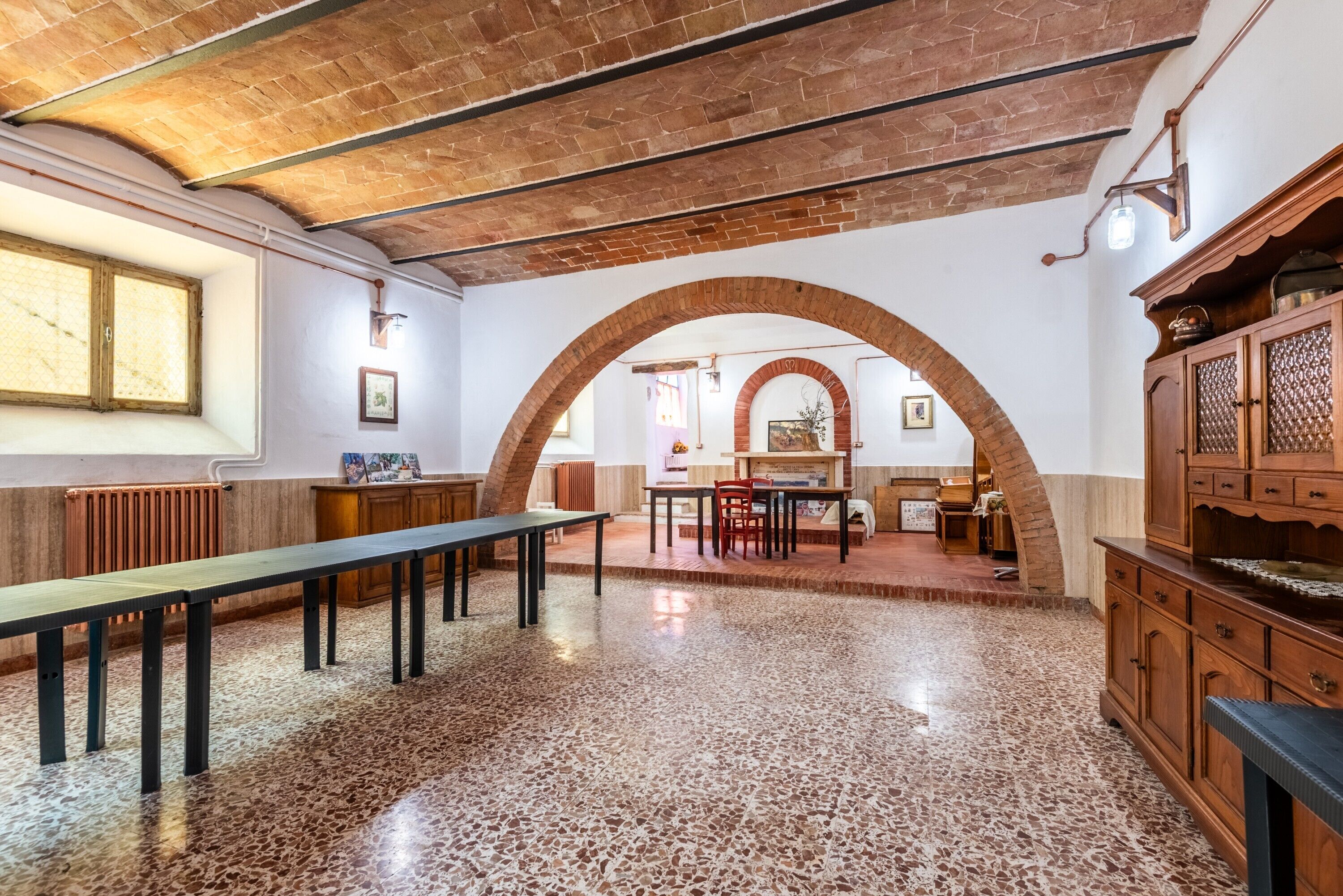 A spacious room with a long table, benches, and a fireplace.