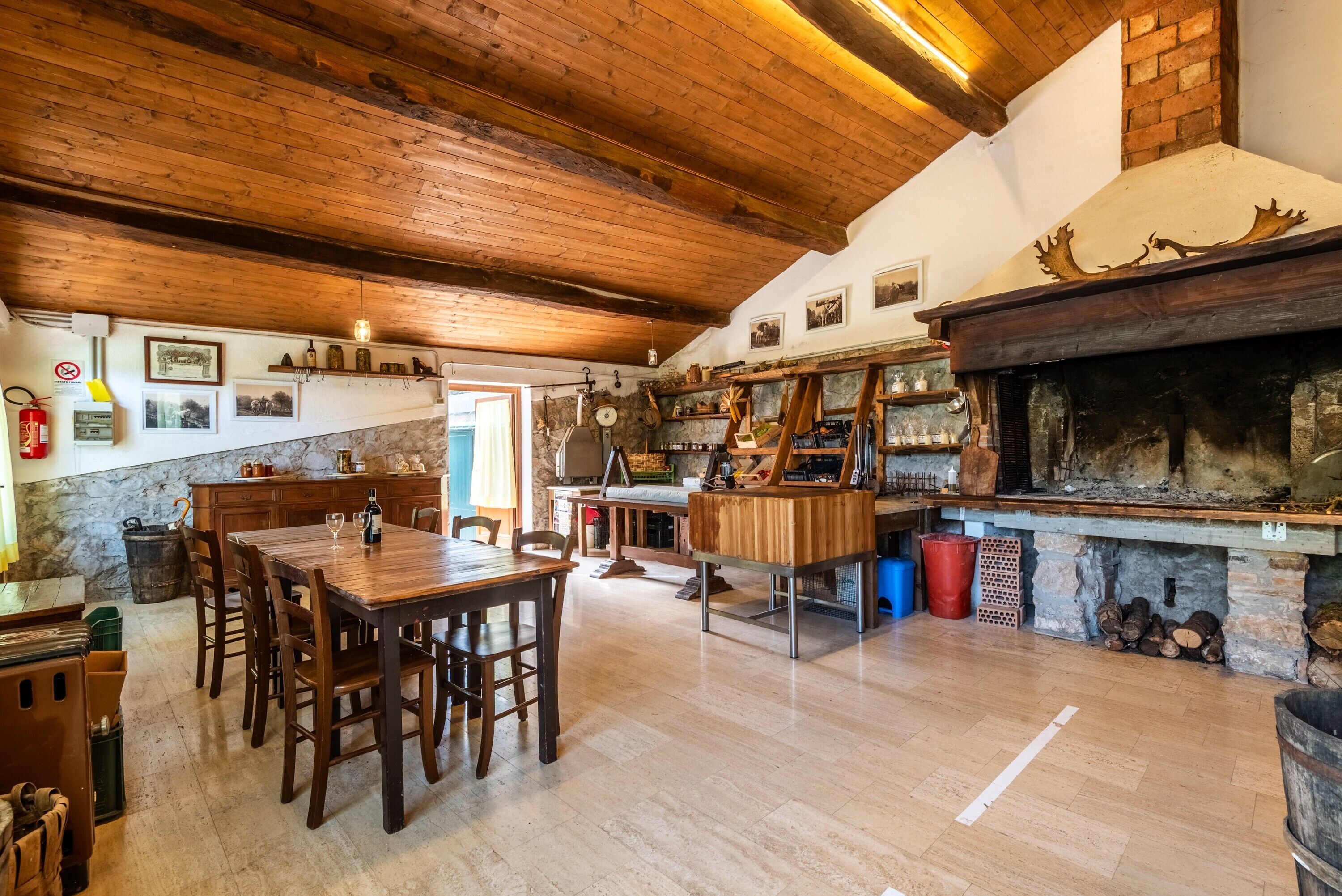 A rustic kitchen with wooden beams, a stone wall, and a fireplace.