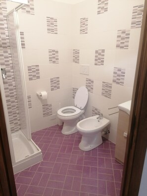 Ein Badezimmer mit Dusche, zwei Toiletten und einem Waschbecken.