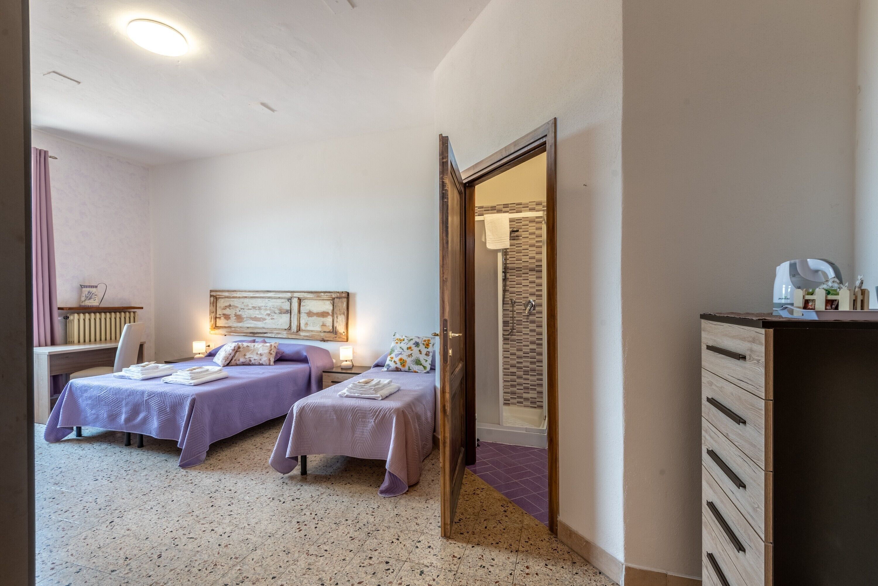 Een slaapkamer met twee bedden, een bureau en een kledingkast.