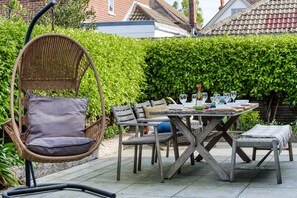 A patio with a wicker chair, a wooden table, and chairs. - 2 Pier Avenue - Whitstable , Kent (Whitstable)
