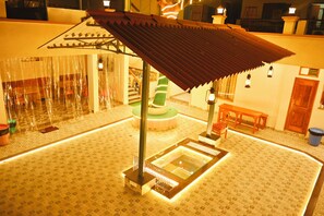 A room with a patterned floor, a central seating area with a bench, a small table, and a decorative column. - Serenitysteay (Varanasi)