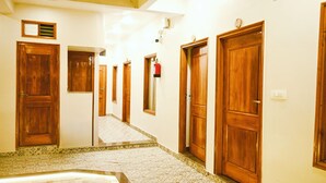 Een hotelgang met houten deuren, een betegelde vloer en een trap naar een hoger niveau.