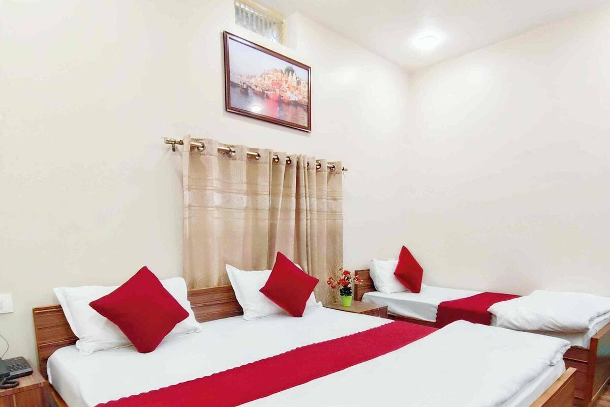 A hotel room with a large bed, two bedside tables, a nightstand, a wall-mounted TV, and a framed picture above the bed.