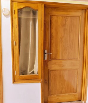 Uma porta de madeira com um painel de vidro e uma maçaneta de metal.