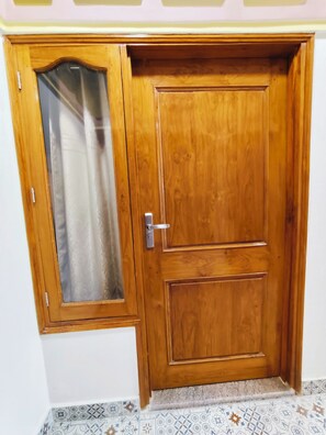 A wooden door with a glass panel and a metal handle. - Serenitysteay (Varanasi)