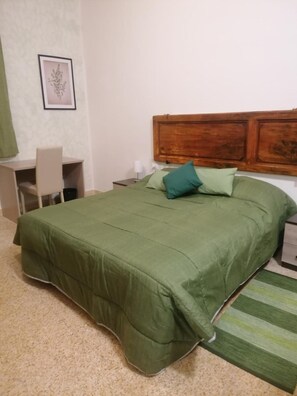 A bedroom with a bed, a desk, and a chair.