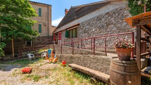Un edificio rústico de piedra con una escalera de madera, un barril de madera y una silla roja.