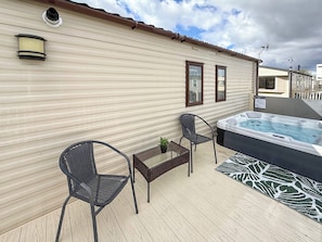 Ein Balkon mit Whirlpool, zwei Stühlen, einem kleinen Tisch und einem Blumentopf.