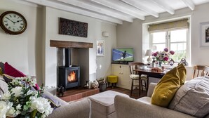 Ein gemütliches Wohnzimmer mit Kamin, Fernseher und Essbereich mit Fenster.