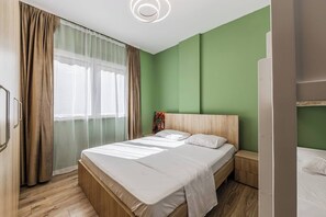 Ein Schlafzimmer mit einem Bett, einem Nachttisch, einem Gemälde und einem Fenster mit Vorhängen.