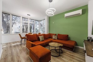 En moderne stue med en modulsofa, et rundt sofabord og et spiseområde med stole.