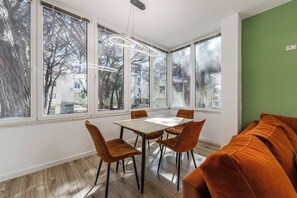 Et moderne spiseområde med et bord, stole, store vinduer og en grøn væg.
