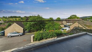A residential area with stone buildings, a parked car, and a clear sky. - Oakwood House (Matlock)