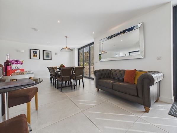 A modern living room with a dining area, a large mirror, and a sofa with a throw pillow. - Oakwood House (Matlock)