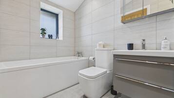 Un baño moderno con bañera, inodoro y tocador.