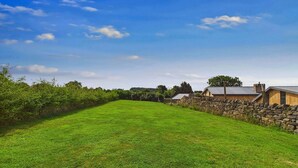 A grassy field with stone walls and buildings in the background. - Oakwood House (Matlock)