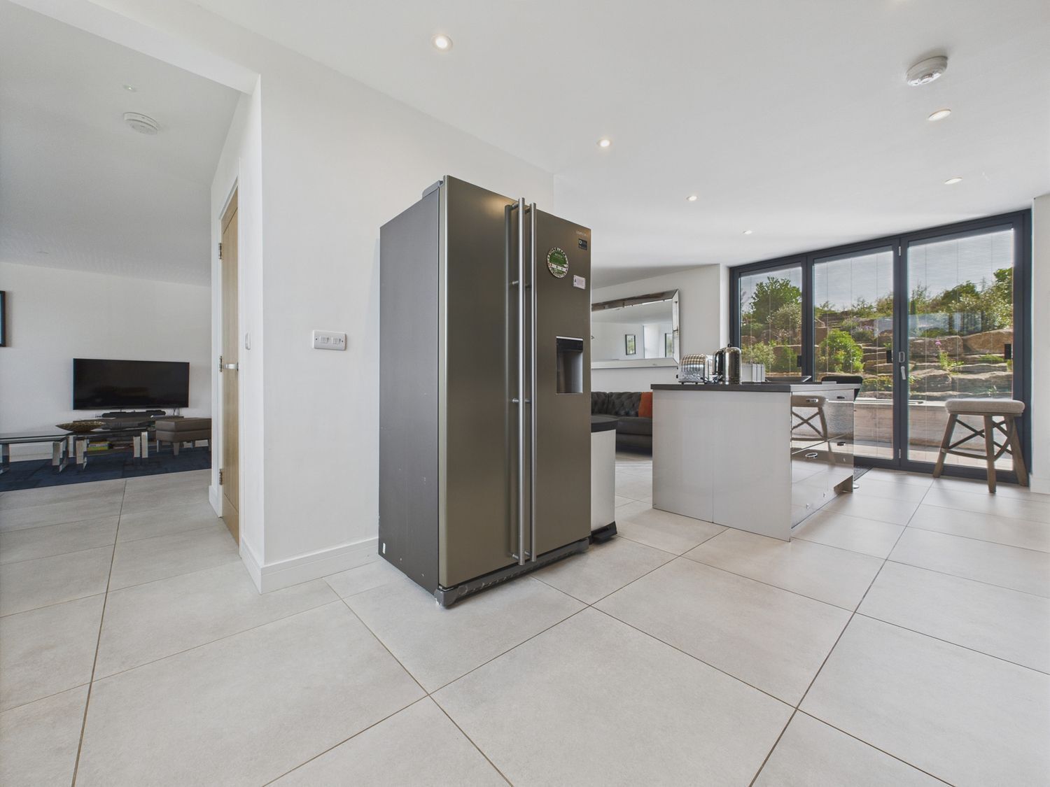 A modern kitchen with a built-in refrigerator, a dining area with a table and chairs, and a large window offering a view of the outdoors.