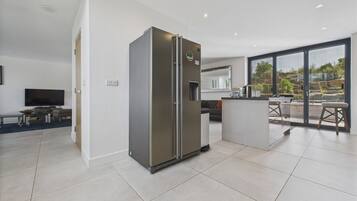 A modern kitchen with a built-in refrigerator, a dining area with a table and chairs, and a large window offering a view of the outdoors.