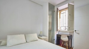 Ein Schlafzimmer mit Bett, Schreibtisch, Stuhl und einem Fenster mit Blick.