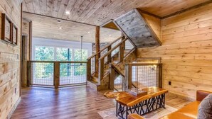 A wooden interior with a staircase, a dining area, and large windows. - Mt LeConte Views • 3 Kings • Sleeps 12 • Hot Tub (Gatlinburg)