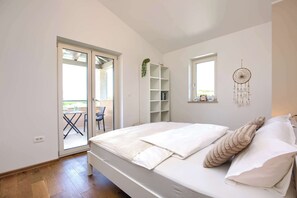 Un dormitorio con cama, ventana, un atrapasueños y puerta corrediza a un área exterior.